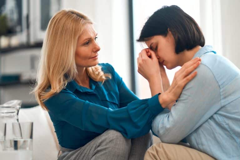 Woman comforting another woman with her head in her hands, worrying about her positive fentanyl test strip