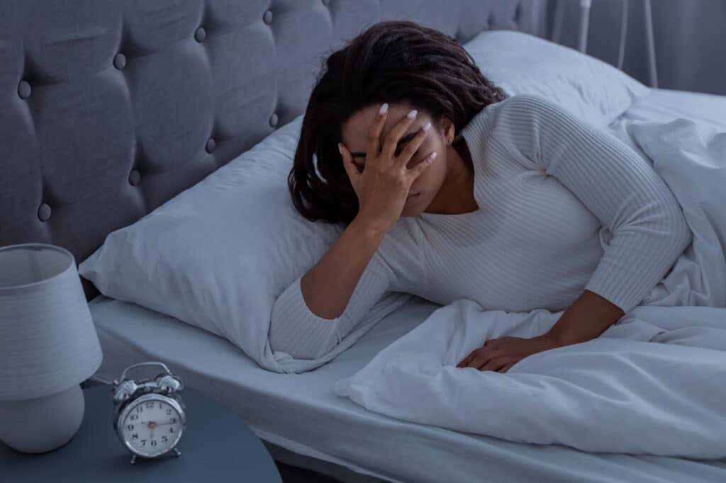 woman with hand over face in bed, wondering, "How long does fentanyl withdrawal last?"