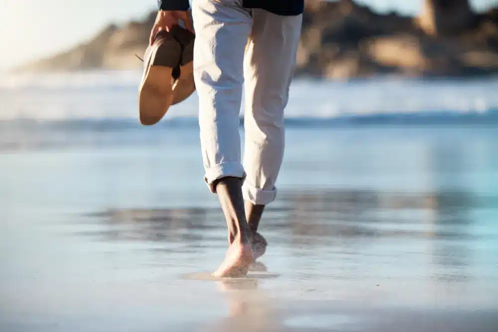 man walking barefoot on beach on break from group therapy for addiction